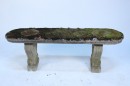 Oval topped cast stone bench retaining its old moss growth